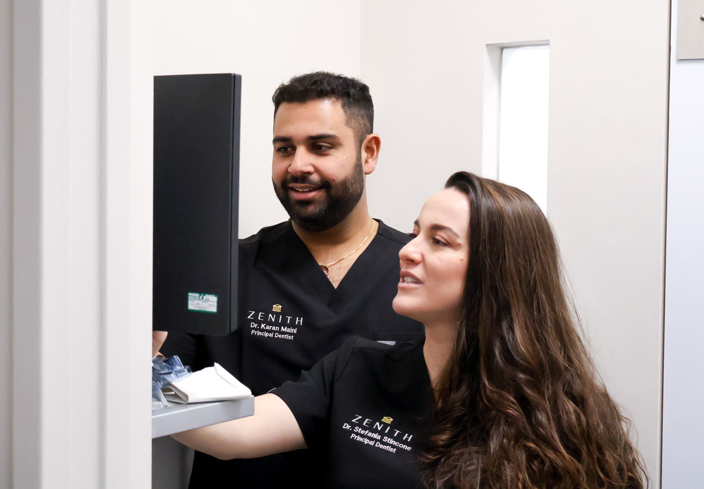 Dr Karan Maini and Dr Stefania Stincone, Zenith principal dentists, examining dental equipment together in a clinic