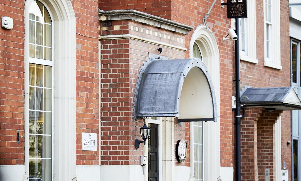 Exterior of Zenith Cosmetic Surgery and Dental Clinic, a red-brick building with arched entrance and branded signage.