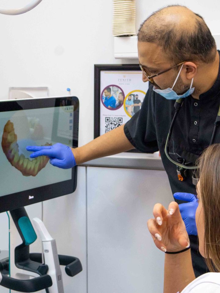 Dentist showing a patient a 3D digital tooth scan on a touchscreen monitor in a dental surgery